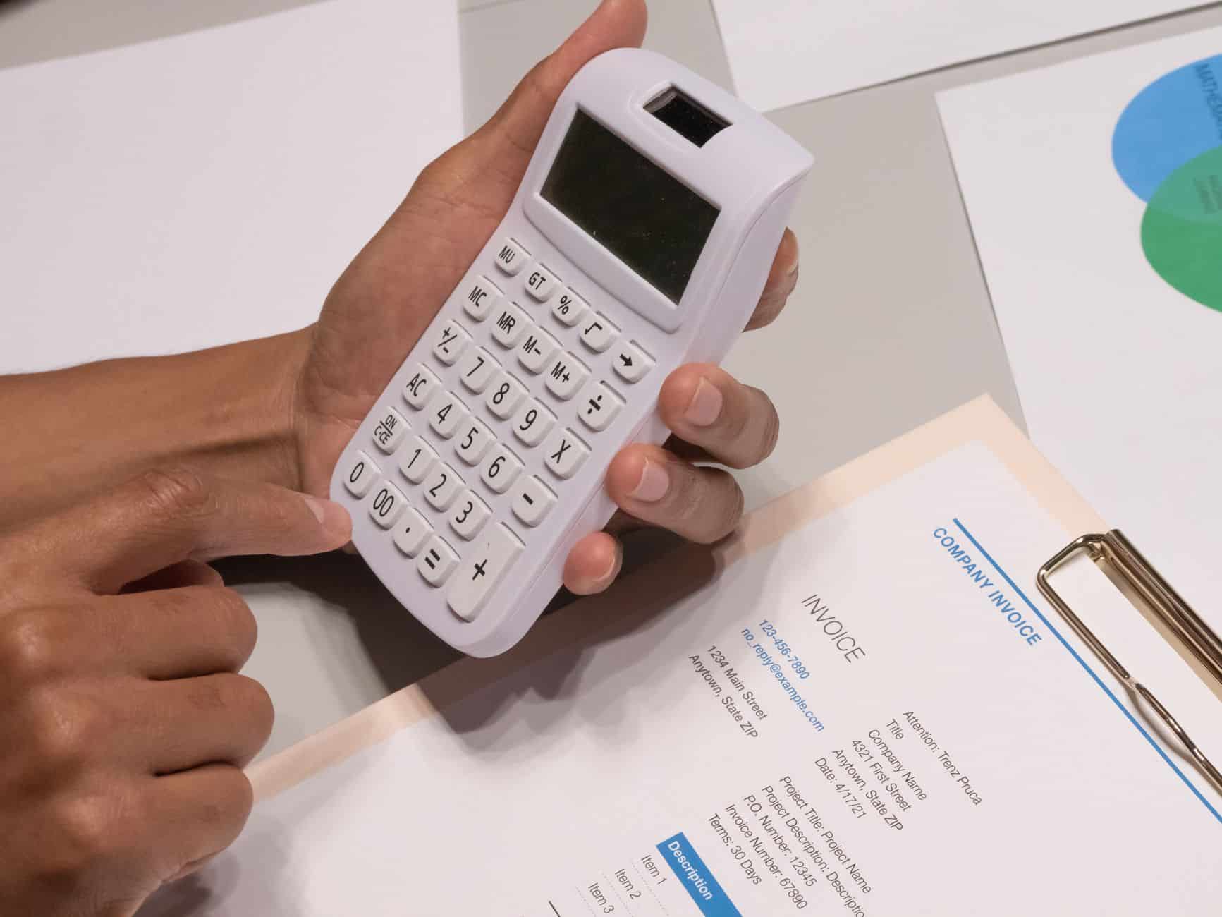 Manos con una calculadora sobre una factura de empresa